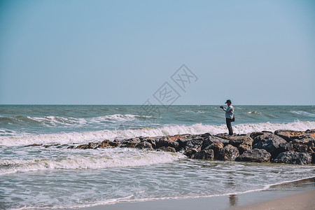 人站在海滩和边的岩石风景上冒险人们山图片
