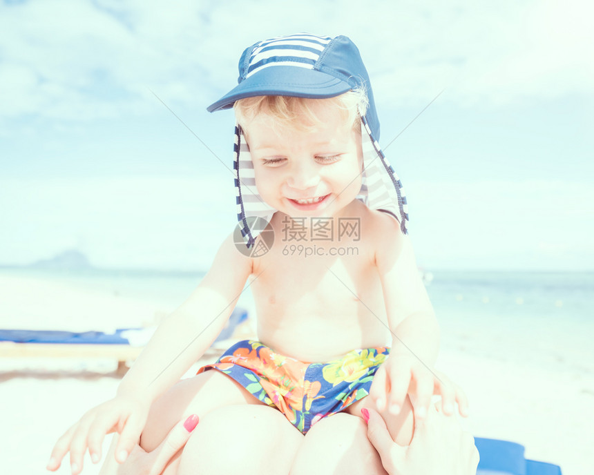 夏天在海滩上坐妈的双腿上坐在母亲身边的婴儿男孩年轻假期图片