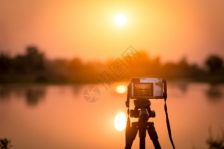 云水太阳将相机设置在三脚架上以记录日落的延时视频背景