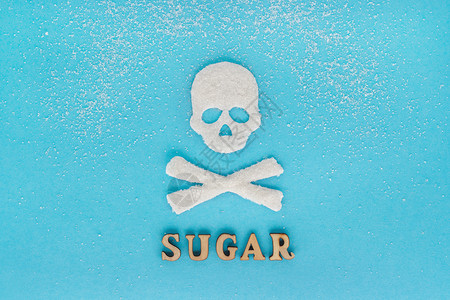 精制糖骷髅糖砂的散射文字蓝色背景概念更多的糖消耗杀死概念大量的糖杀死骷髅b有害疏散甜点设计图片