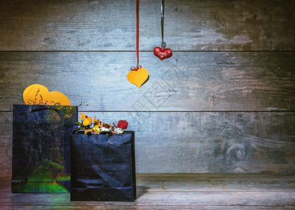 两包纸袋和一对挂在古旧黑木背景上的心情人节礼物有质感丝带自制图片