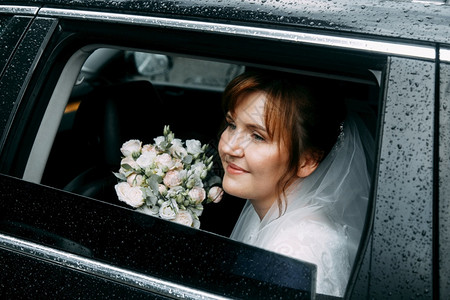 新娘车白色的时髦雨天露浅地深处在车窗户上用花束贴近新娘的距离肖像女背景