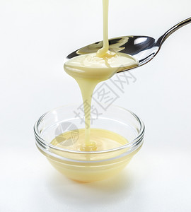 以白色背景的茶匙为原料用冷冻牛奶和茶勺进行缝合式灌注吃胖的碗图片