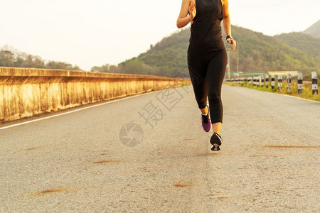 日落女运动员在一条健康道路上奔跑的妇女运动小路行图片