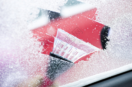 白种人从汽车挡风玻璃上刮雪和冰霜不开心图片