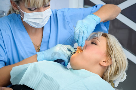 女牙医给病人牙齿做手术背景图片