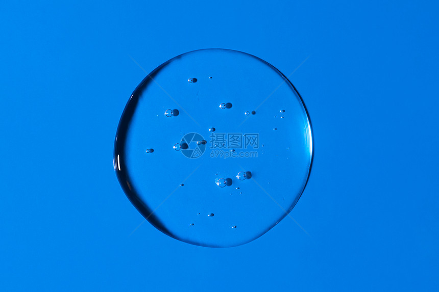 弄脏在蓝色背景上隔离的透明圆形液体凝胶滴或涂片顶视图保护或化妆品概念血清质地在蓝色背景上隔离的透明圆形液体凝胶滴或涂片血清质地气图片