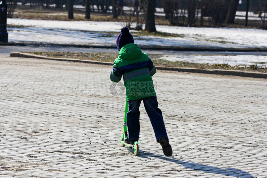 爱好男孩在寒冷的季节骑着滑雪车在公园路边上走着球场户外小型摩托车图片