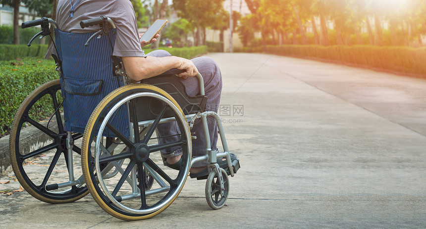 阳光男在公共园地区休息时轮椅上残疾人的中间部分在使用智能手机29禁用图片