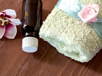 毛巾水浴用油瓶和木底按摩用头背景的按摩毛巾和一瓶油为了木制的结石图片