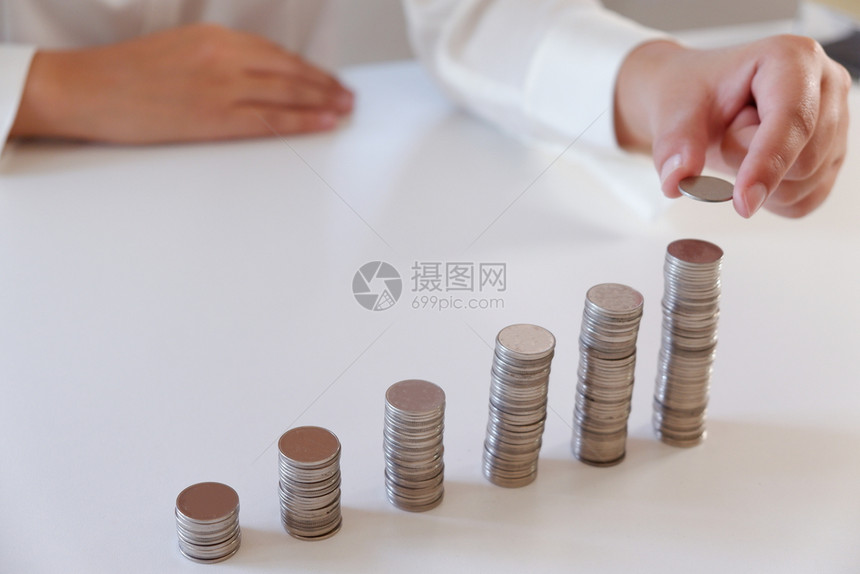 超过桌子商业界人士将硬币放置在增加的硬币堆叠上投资图片