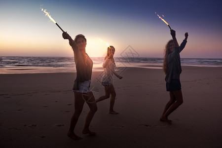 保持青少年朋友在海滩上玩烟火跑幸福闪烁高清图片