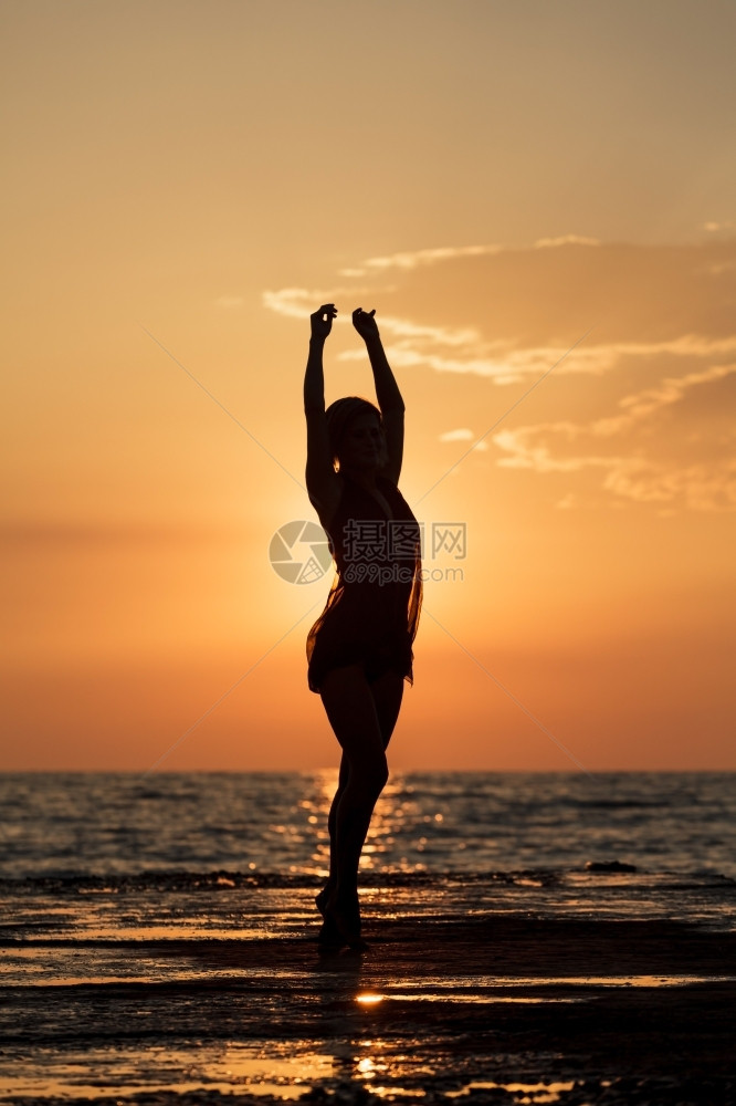 波浪热带快乐的在日落时跳舞一个女孩在海上日落背景跳舞的西尔休埃特舞图片