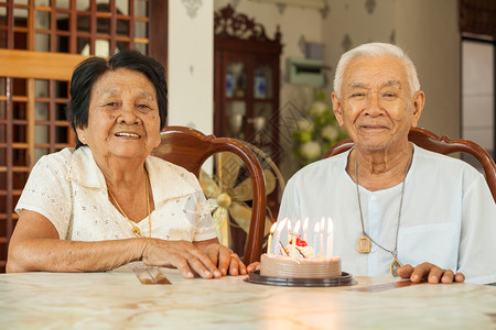 闲暇亚洲高龄夫妇在客厅里拿着蛋糕笑家庭女士图片