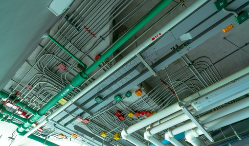 电气安装在聚氯乙烯排水系统塑料管道和工业建筑天花板造上清洁水的电路管道系统和动钢管缆安装在聚氯乙烯上限排水系统塑料管道上工业的红背景图片