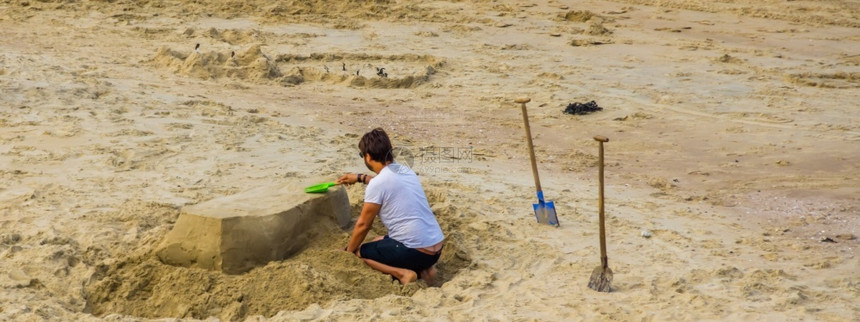 夏天有创造力的成年男在海滩上雕塑沙堡娱乐和创造户外活动一种图片