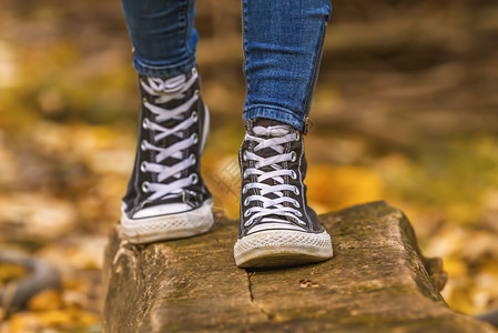 黑色的秋季天女孩穿着黑色运动鞋在落叶上用木头行走穿黑色运动鞋黄的蓝图片