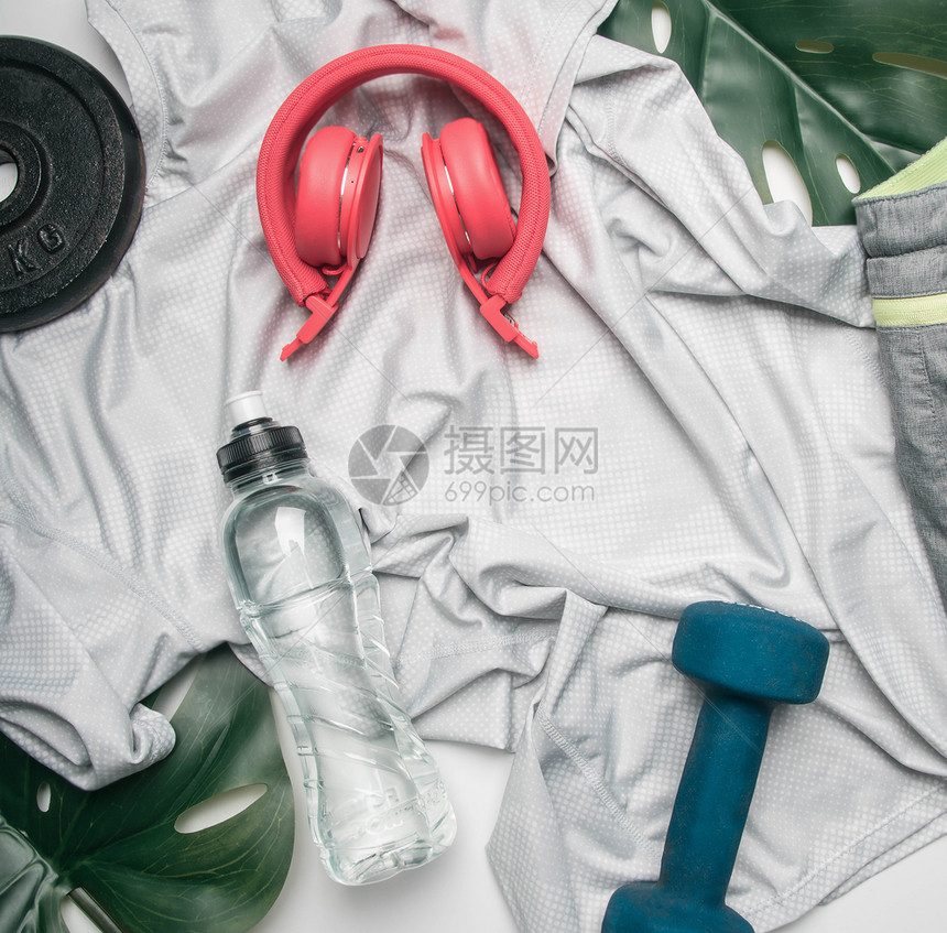 目的运动苗条生活方式服装耳机哑铃排在白色背景上装有一瓶水和热带叶文字空间等体育概念图片