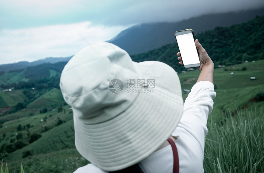 外部旅游者享受大自然在山地背景上用智能手机拍照技术移动的图片