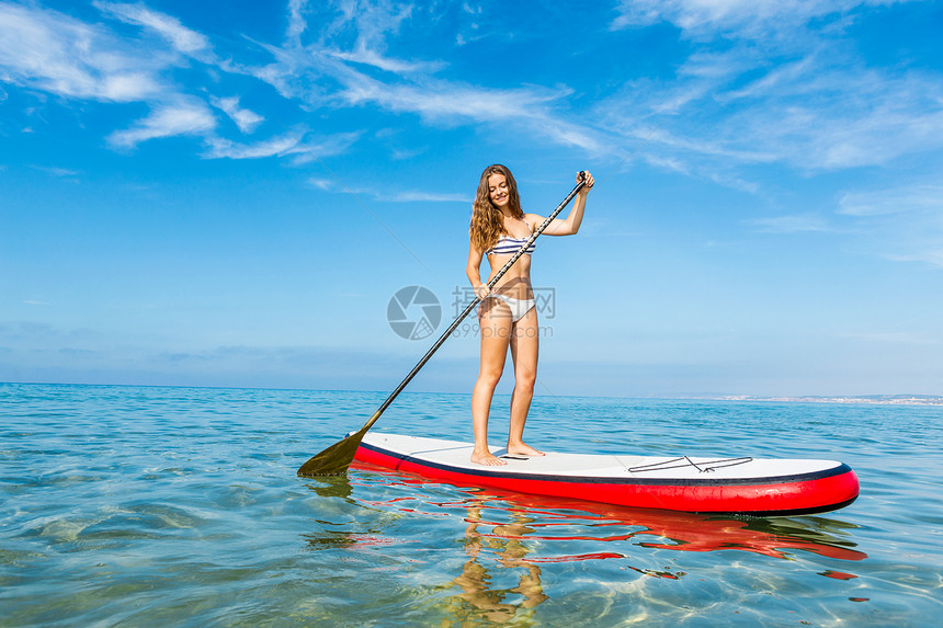 一个美丽的女人在阳光明媚的日子里练习划桨海滩夏天女孩图片