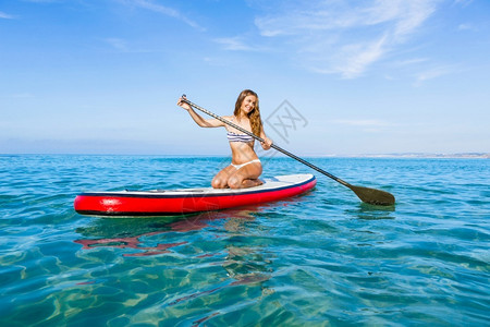 一个美丽的女人在阳光明媚的日子里练习划桨假期水上运动晴天图片
