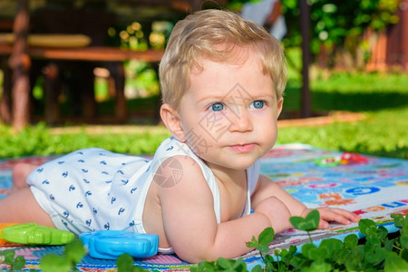 脸夏天男生美丽的小孩8个月大在花园里爬来去图片