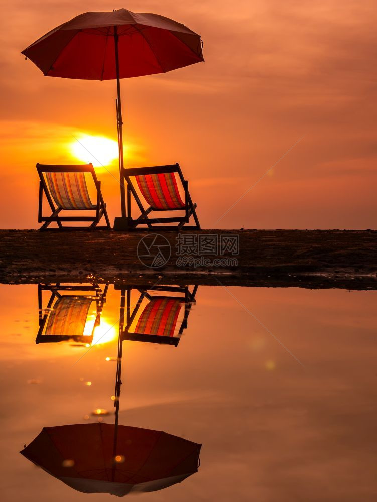 太阳升起海面上有橙色的清晨天空泰国水中海滩反射上有椅子和雨伞冷静的私人阳光图片