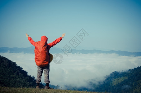 早晨常设山顶上背着包的爬山者享受着闪电图片