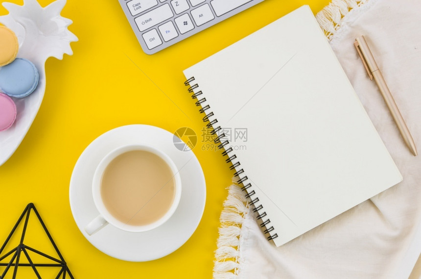健康品尝黄色背景下的茶杯马卡龙螺旋笔记纸桌布液体图片