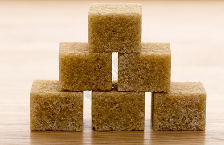水晶木制背景上的棕甘蔗糖方块Macro棕色甘蔗糖方块木制背景的黄色图片