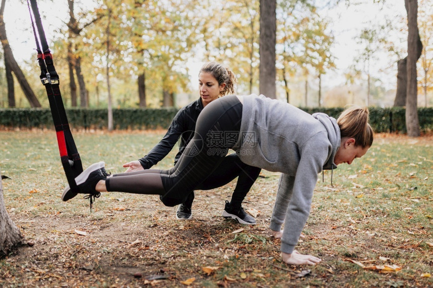 年轻的拉紧公园外与trx一起训练的女公园外与trx一起训练的女锻炼图片