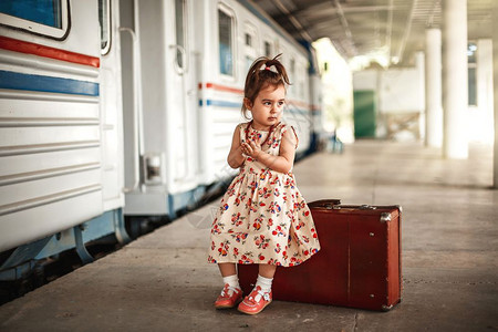 快乐的在小火车站穿着旧衣服和行李箱的可爱白种女孩小火车站童年图片
