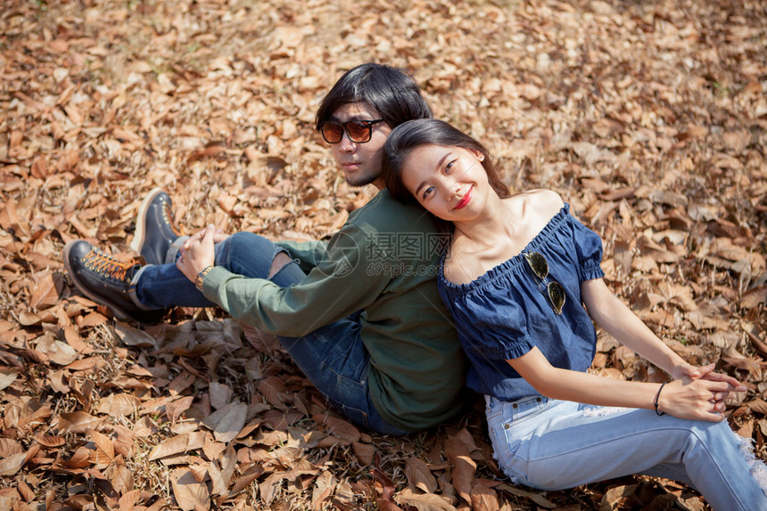 好的婚姻随意年轻亚洲男人和女在地面干叶上放松的肖像图片