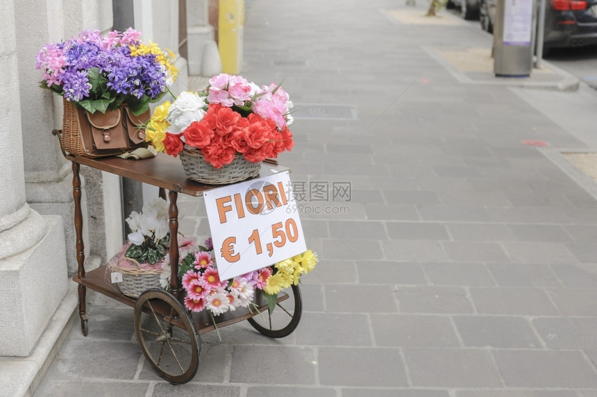 一辆配有过压篮子的马车和一个装满鲜花供出售的老鱼叉篮子外部的优质目图片