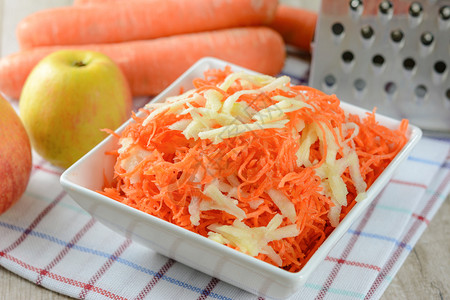 苹果分割去核器准备健康沙拉的构想将胡萝卜加在白色盘子中的苹果放在草莓胡萝卜和苹果的背景上白色磨碎可口背景