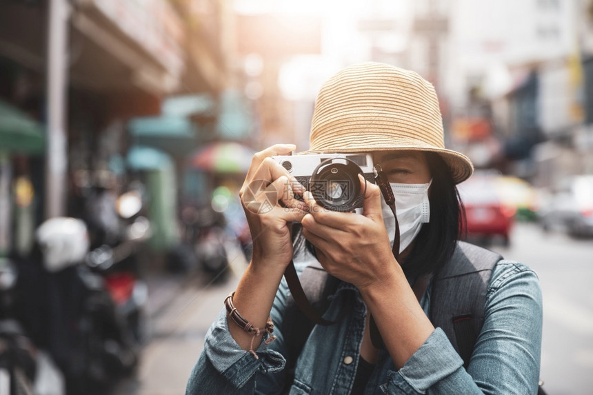 感染社会的身穿外科面罩的亚洲妇女旅行者与摄影照片肖像户外夏季概念复古的图片