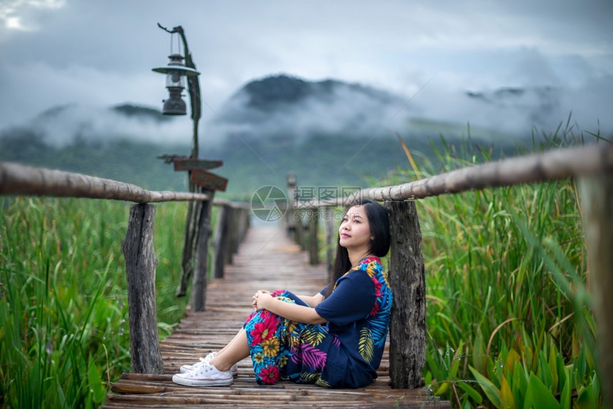 山年轻的坐在码头上女人看着日落的美丽早晨图片