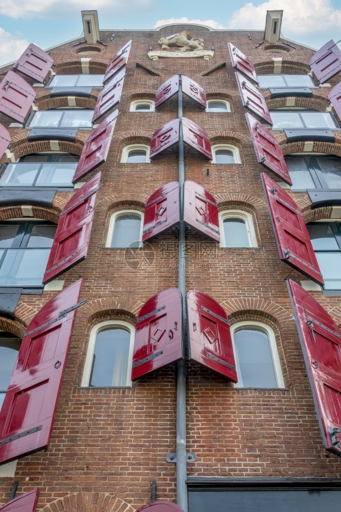 正面外部的天空荷兰在阿姆斯特丹的一天个旧砖房的景象一个旧砖房的窗户上开着红色百叶窗在阿姆斯特丹的旧房子上装着红色百叶窗在Wind图片