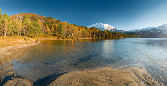风景优美天空挪威风景包括湖泊秋林和远处雪覆盖的山丘旅行图片