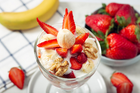 含有草莓香蕉酸奶和核桃健康食品概念的玻璃中健康甜点茶白色的燕麦图片