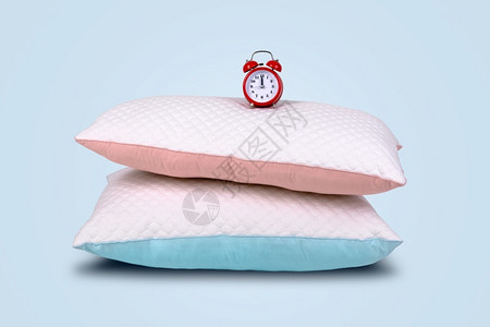 有创造力的羽毛两种现代枕头和红色闹钟蓝底睡眠时间概念床头板图片