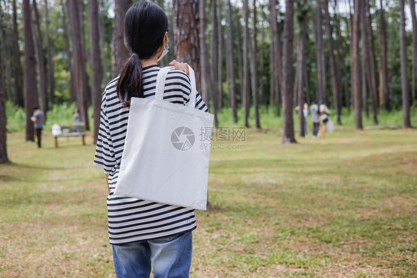 妇女在公园中持有白色棉花袋的妇女有机孩面具图片