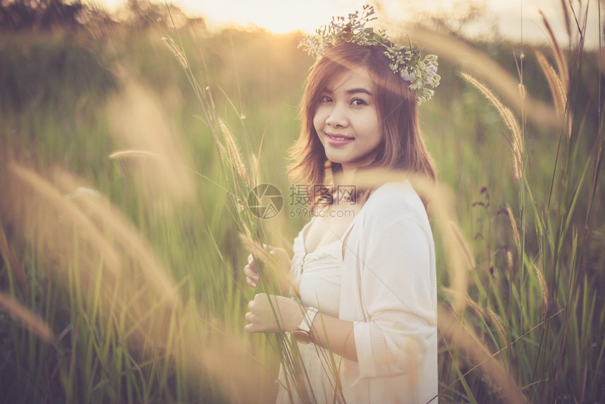 日落时在金田上摆姿势的年轻亚洲女人优质的快乐太阳图片
