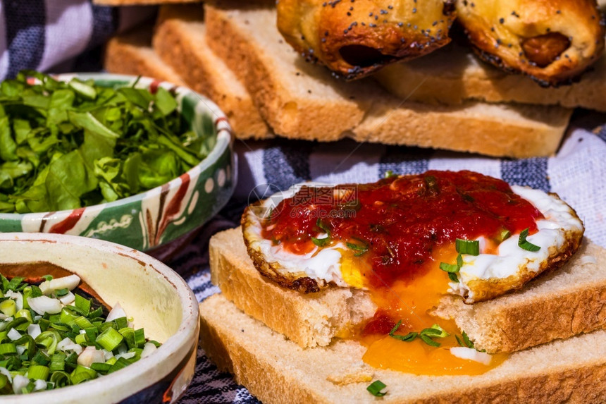 绿色健康香肠卷面包上煎蛋加酱汁和切碎蔬菜的不同碗面精美配香肠卷烤面包上的炒蛋不同碗洋葱图片