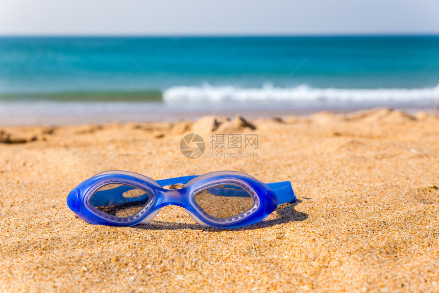 蓝色游泳护目镜躺在沙滩上图片