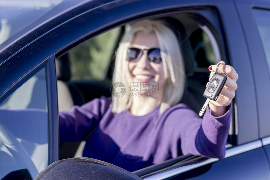 漂亮的快乐女司机在她新车里拿着钥匙微笑里面图片