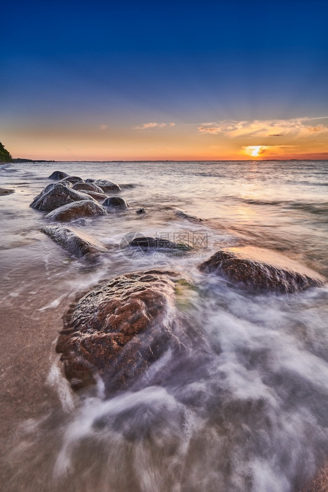 海边击打岩石的浪花与夕阳图片