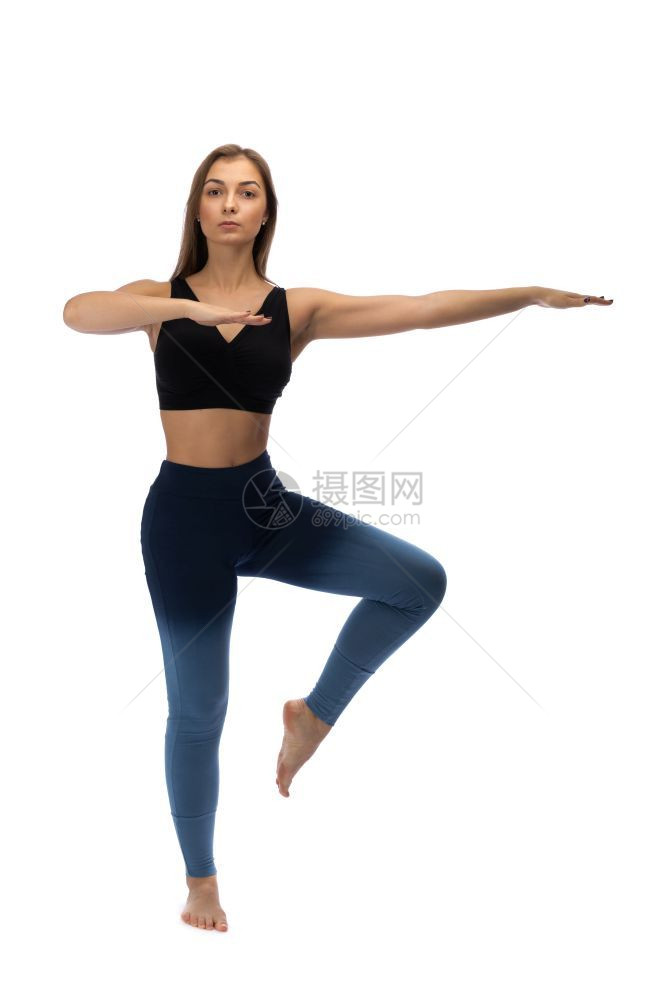 练习专业的女孩在一个白色背景的演播室里做瑜伽摆姿势图片