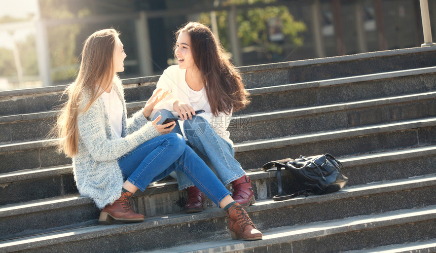 肖像移动的人们两位快乐女青少年在街上一起聊天坐在楼梯上Stairs图片