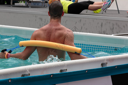男子在游泳池做水有氧运动与流棒游泳的小面条一起游泳肌肉发达美丽的训练图片